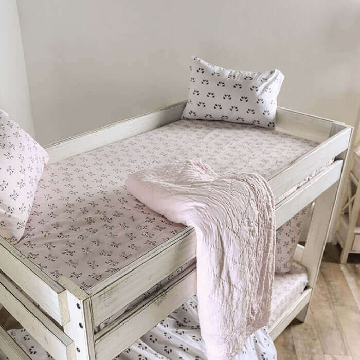 Cozy bunk bed with rustic white finish, featuring floral bedding and soft pillows in a bright, airy bedroom.