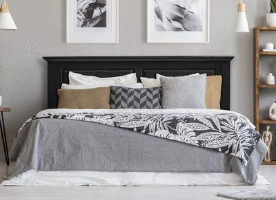 Cottage style ebony headboard in a modern bedroom with decorative pillows and stylish bedding on a neatly made bed.