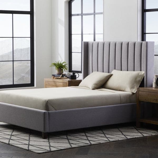 Modern bedroom featuring Malouf Smooth Driftwood Bamboo Rayon Pillowcase Set on a stylish gray bed frame and soft beige sheets.
