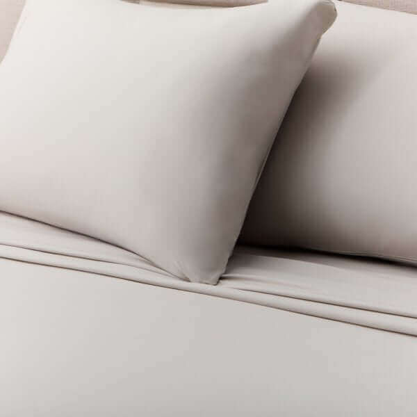 Soft beige Malouf Driftwood microfiber sheet set with cozy pillows on a bed, showcasing a velvety texture and wrinkle-resistant material.