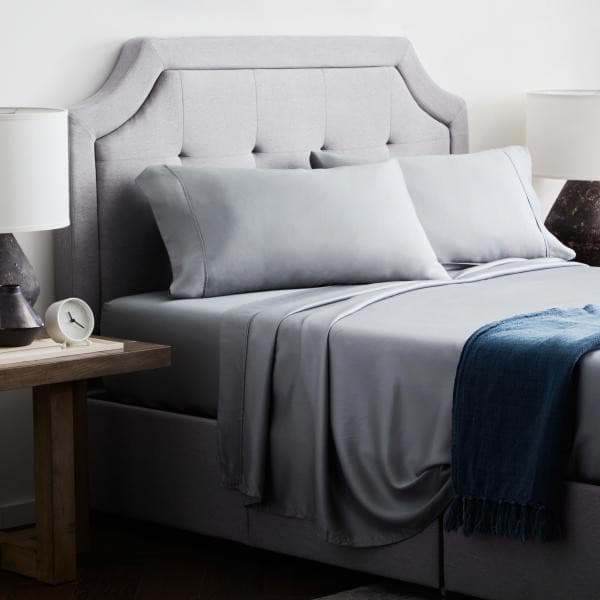 Elegant bedroom featuring Malouf Dusk Botanical Tencel™ Lyocell sheet set in soft gray with modern decor and bedside lamps.