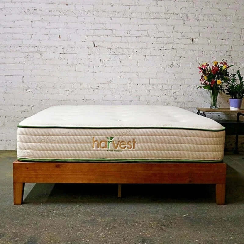 Harvest Green Original GOTS Certified 11" mattress on a wooden bed frame in a rustic setting. Eco-friendly and organic design.