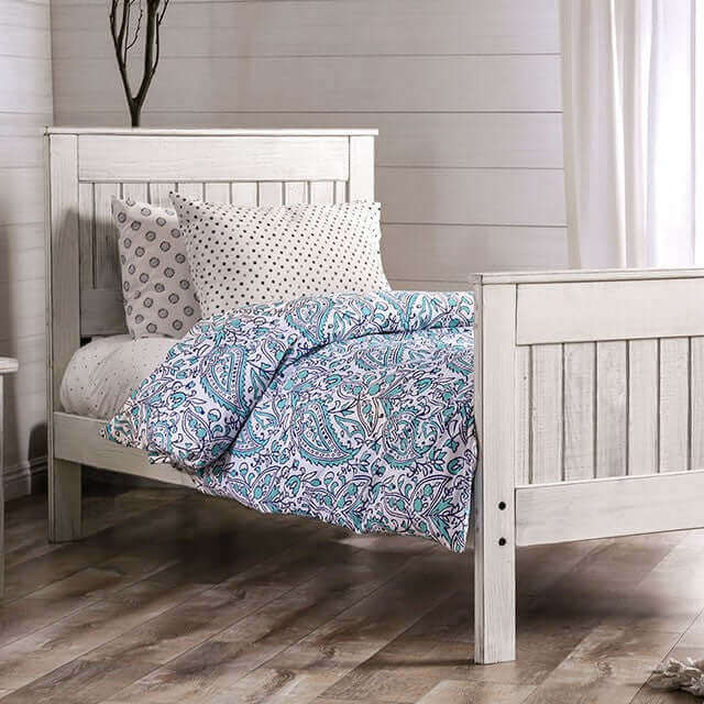 Brushed white panel bed with colorful bedding and decorative pillows in a cozy bedroom setting.