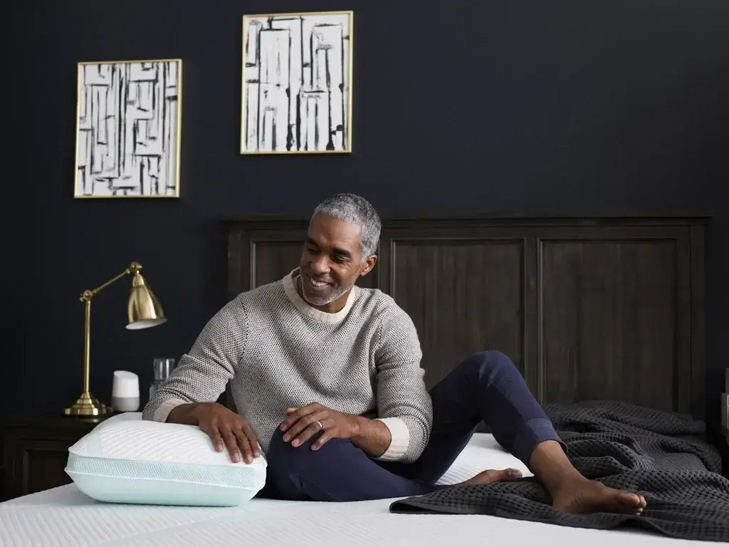 Man enjoying the Tempur-Adapt ProHi + Cooling Pillow on a stylish bed, demonstrating comfort and relaxation.