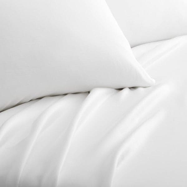 Close-up of Malouf white Tencel™ Lyocell pillowcase and sheets showcasing soft, smooth fabric texture.
