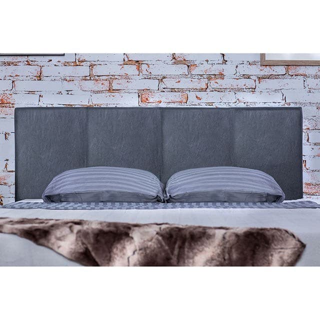 Modern gray padded headboard in a contemporary bedroom setting with striped pillows and a textured throw.