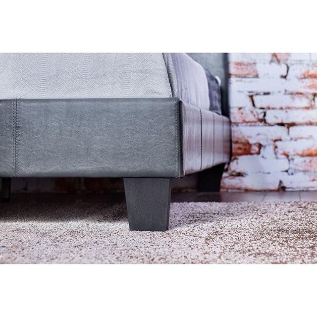 Close-up of the Winn Park Gray Platform Bed showcasing its padded headboard and contemporary legs against a textured background.