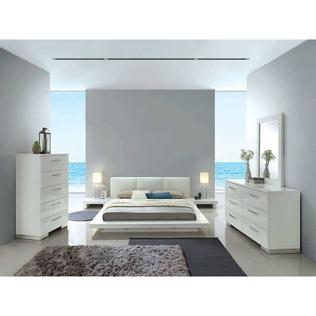 Modern white platform bed in a sleek minimalist bedroom with ocean view, featuring low-profile nightstands and stylish furniture.