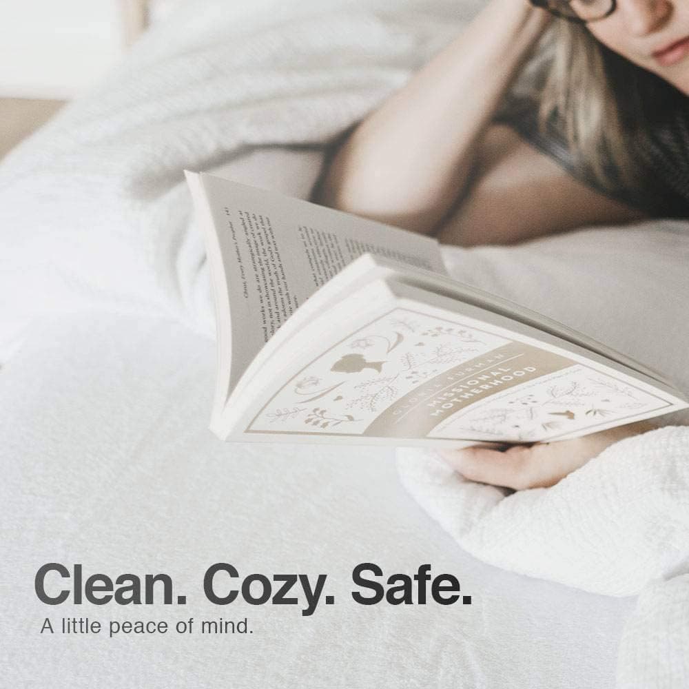 Person reading a book on a cozy mattress with a soft, clean mattress protector for added safety and comfort.