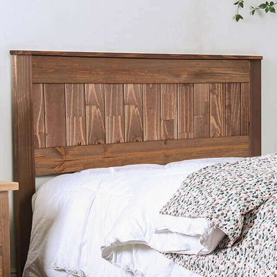 Rustic mahogany wood headboard above a cozy white bed with patterned bedding, adding warmth to the bedroom.