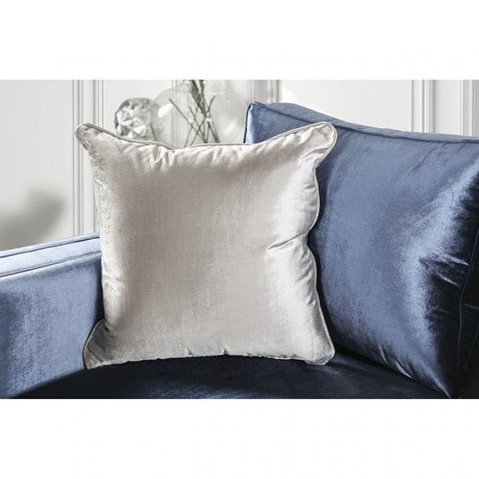 Close-up of silver decorative pillow on a blue satin sofa, showcasing elegant texture and contemporary design.