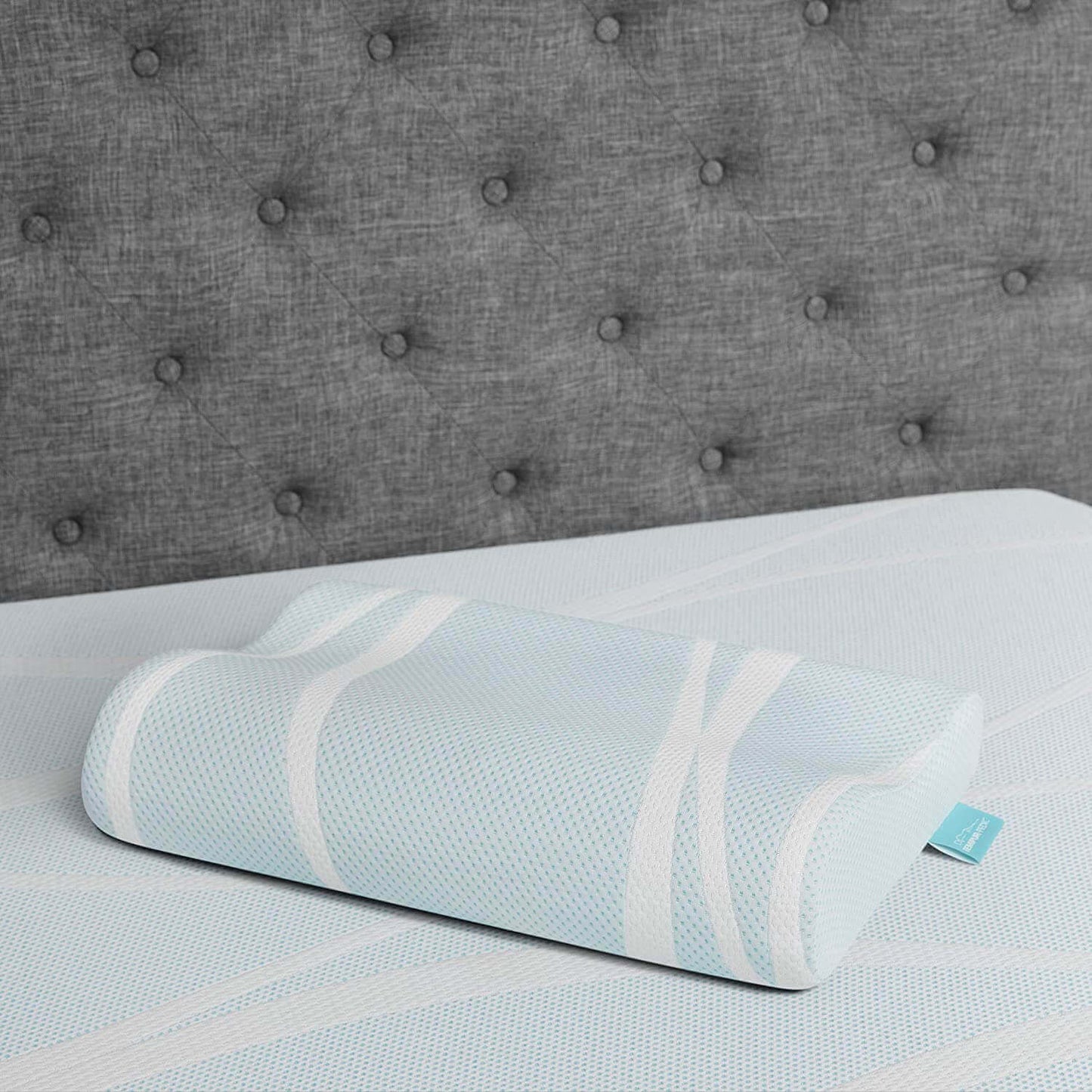 Tempur-Breeze° Neck + Advanced Cooling Pillow on a soft mattress, featuring a cool blue design and ergonomic shape for comfort.