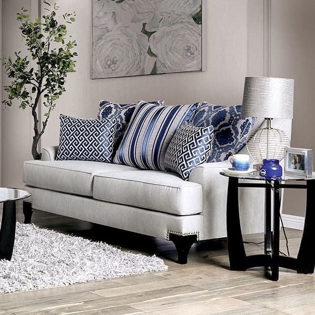 Light gray transitional loveseat with decorative pillows, accent table, and floral artwork in modern living room setting.