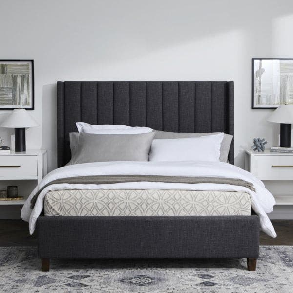 Modern grey upholstered bed with decorative pillows and stylish nightstands in a minimalist bedroom setting.