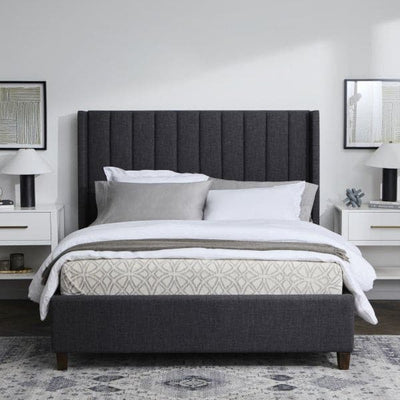 Elegant gray upholstered bed with plush bedding and stylish bedside lamps in a modern bedroom setting.