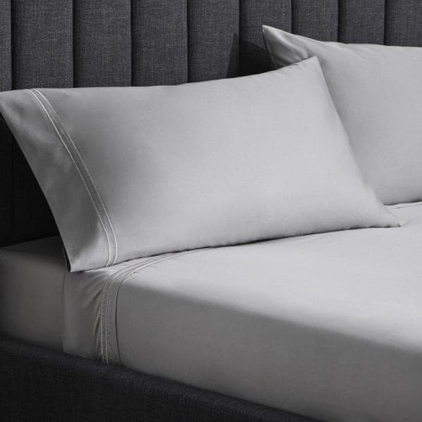 Luxurious Malouf Premium Flax Natural Supima Cotton Pillowcase Set on a stylish bed with a gray backdrop.