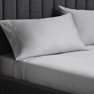Luxurious Malouf Premium Flax Natural Supima Cotton Pillowcase Set on a stylish bed with a gray backdrop.