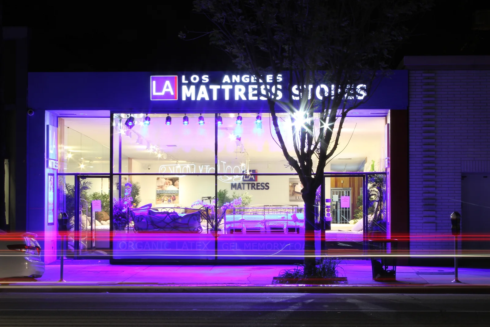 The illuminated LA Mattress storefront on Ventura Boulevard at night, with the showroom visible through its windows