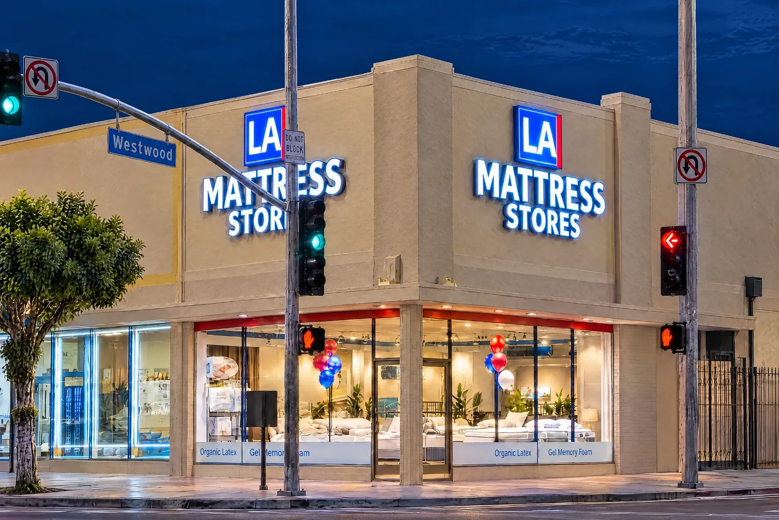 The West LA showroom on the corner of Pico Boulevard and Westwood Boulevard at dusk, its LA Mattress Stores signs lit