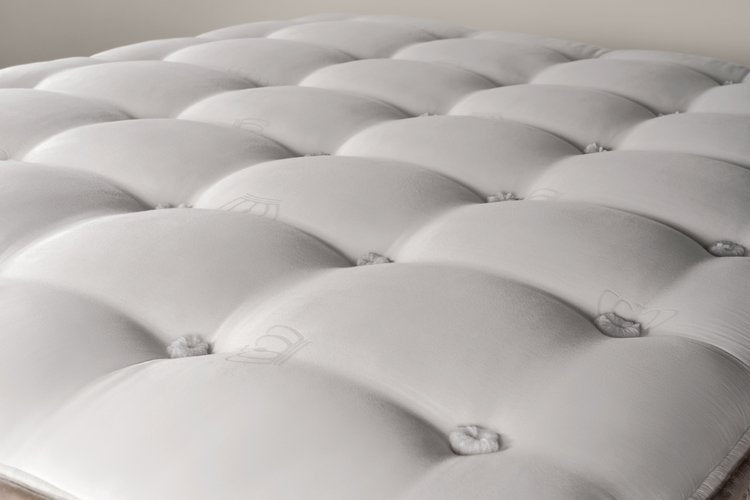 Close-up of a plush, tufted mattress surface showcasing its soft, cushioned texture and elegant design.