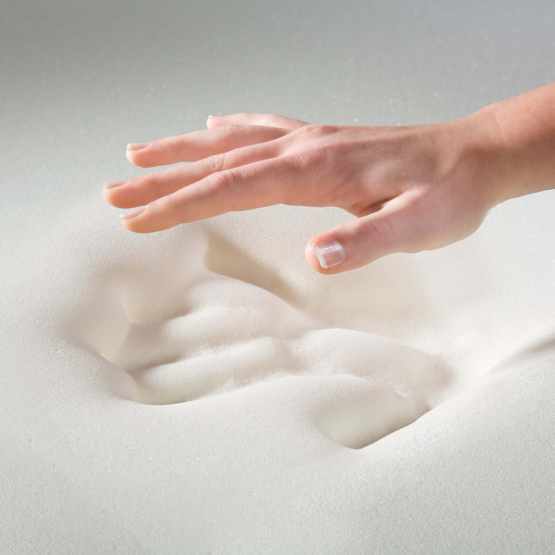 Hand pressing into soft foam material, showcasing a deep imprint for comfort and support.