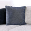 Dark blue textured throw pillow on a gray sectional sofa, adding comfort and style to the living room decor.