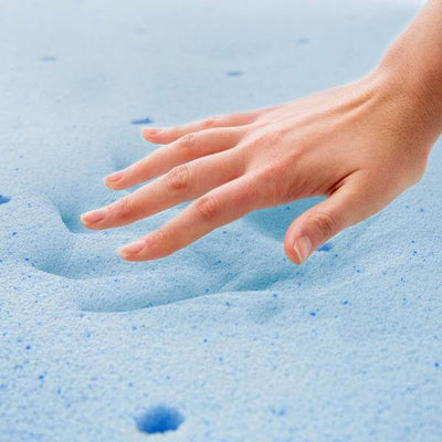 Hand gently pressing into soft blue memory foam mattress, showcasing comfort and support.