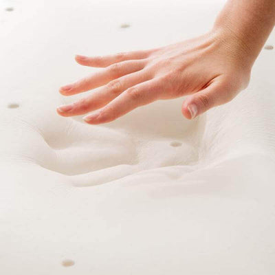 Hand pressing a soft Malouf memory foam mattress topper, showcasing its comfort and responsiveness.