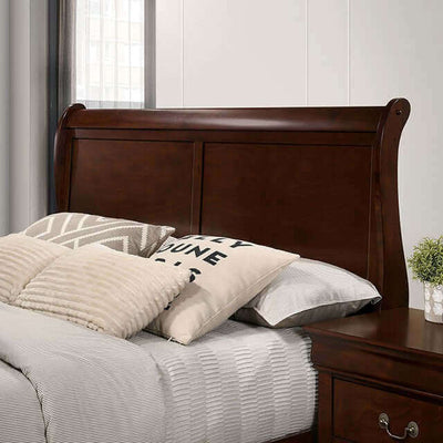 Louis Philippe cherry sleigh bed headboard with decorative pillows and gray bedding in a stylish bedroom setting.