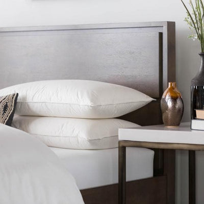 Malouf Z™ TripleLayer™ Down Pillow stacked on a stylish bed with decor items nearby.