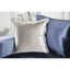 Close-up of silver decorative pillow on a blue satin sofa, showcasing elegant texture and contemporary design.